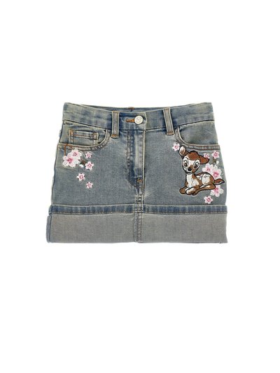 Jupe en denim bleu clair avec ourlet roulé. Présente un motif floral brodé et un motif de cerf cartoon à l'avant. Style à cinq poches.