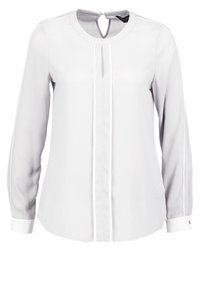 Blouse à manches longues en gris clair, confectionnée dans un tissu lisse. Elle présente une encolure en forme de goutte et un liseré blanc le long du devant et des manches.