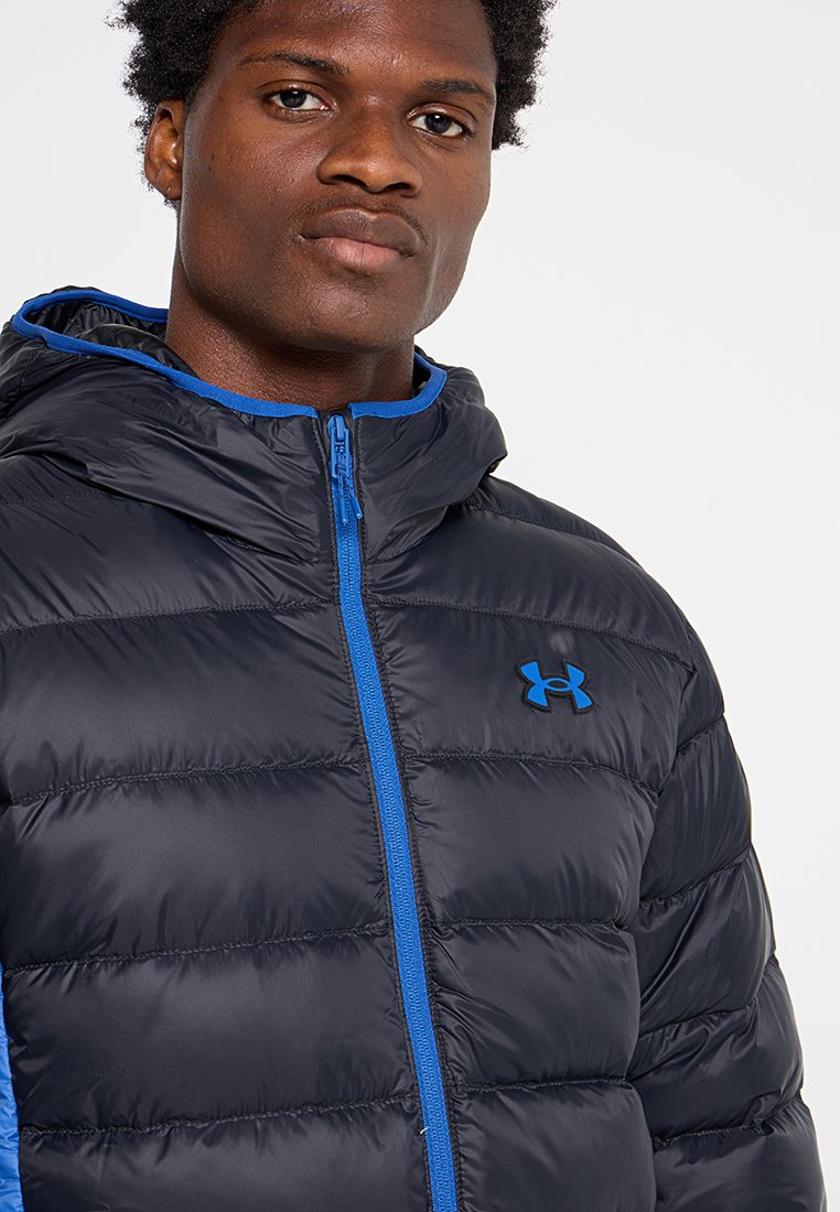 Doudoune marine avec des accents bleus, dotée d'une fermeture éclair, d'une capuche et d'une texture matelassée. Logo Under Armour sur la poitrine gauche.