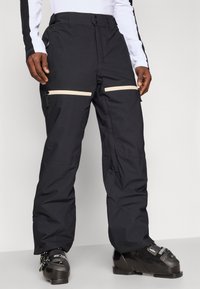 Fekete hó nadrág, laza szabással, két cipzáros zsebbel, világosszürke részletekkel és megerősített szegélyekkel, tartós anyagból készült.