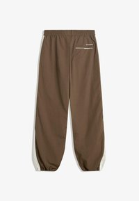 Brown elastic waist pants with side seams in cream, featuring a small front pocket and gathered cuffs. Smooth texture and lightweight fabric.