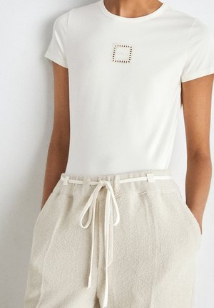 Biały dopasowany top z krótkim rękawem i małym kwadratowym logo „Boss” na piersi, zestawiony z wysokim stanem teksturowanych spodni ze ściągaczem.