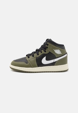 Basket montante avec panneaux vert olive, noir et blanc, logo Nike blanc, lacets noirs et logo Air Jordan Wings sur la cheville.
