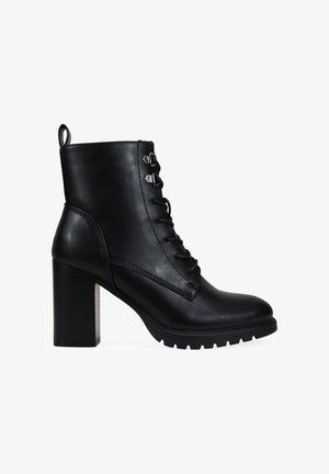 Stivaletto in pelle nera con lacci sul davanti, tacco spesso e suola testurizzata. Presenta dettagli in metallo argentato e una linguetta sul retro per indossarlo facilmente.