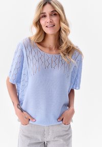 Lichtblauwe gebreide trui met korte mouwen, voorzien van een textuur en opengewerkt ontwerp en een geribbelde zoom, gecombineerd met gestreepte broek.