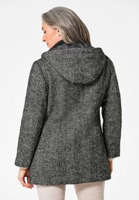 Zwart-wit herringbone gepatterneerde jas met capuchon, voorzien van een textuurstof en een getailleerde silhoutte, zichtbare naden en lange mouwen.