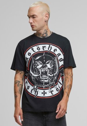 Sort bomulds T-shirt med et stort hvidt og rødt grafisk motiv af et kranium med horn og kæder, rundt design med teksten "Motörhead".