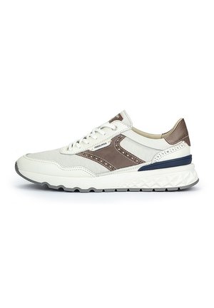 Zapatilla deportiva blanca con acentos marrones, que presenta un upper texturizado, detalles perforados y una suela de goma de múltiples capas.