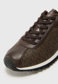 Baskets brunes avec un mélange de cuir lisse et de textile à motifs, design à lacets, surface texturée et semelle en caoutchouc avec traction.