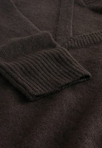 Dark brown wool sweater featuring a V-neck, ribbed cuffs, and a soft, textured surface. Focus on fabric details and knit pattern.