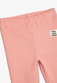 Pantalons en tissu ribbé rose avec une taille élastique et une petite patch portant l'inscription "Faites un bon choix !" près de la hanche gauche.
