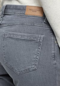 Halli teksapüksid sirge lõikega, mille vöökohal on nahast brändisilt ja tagataskul kontrastse õmblusega.