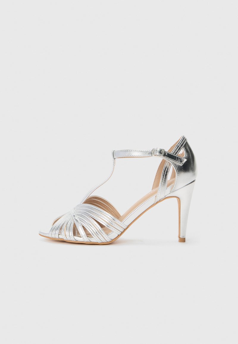 Silberne Riemchen-High Heels mit offener Zehenpartie, die ein glattes, metallisches Finish und einen schlanken Knöchelriemen mit Schnalle aufweisen.