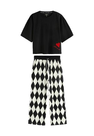 Black cropped t-shirt with red heart and "REBEL OF LOVE" text; paired with black-and-white diamond-patterned wide-leg pants.