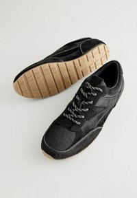 Scarpe sportive nere caratterizzate da una combinazione di materiali lisci e testurizzati, con punta rotonda, lacci a motivo e suola in gomma naturale.