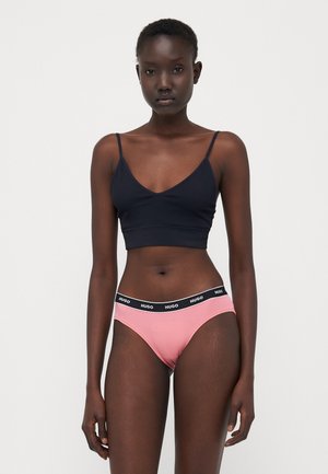 Zwarte katoenen bralette met dunne bandjes en een V-hals, gecombineerd met roze onderbroekjes met een zwarte elastische tailleband met het "HUGO" logo.