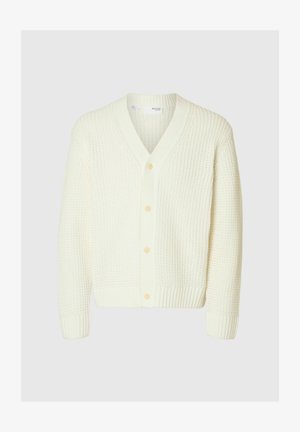 Kārta ar V-veida kaklu, ilgiem piedurknēm, ribotām aprocēm un apakšmalu, krēmkrāsā, ar četriem pogu slēdzenēm priekšpusē.