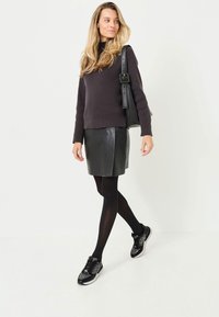 Mørkegrå ribbet sweater, sort læder mini nederdel, sorte strømpebukser og mønstrede sorte sneakers. Enkel håndtaske over skulderen.
