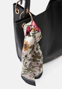 Black leather tote bag with textured finish, featuring a floral-patterned silk scarf tied at one handle and gold-tone hardware accents.