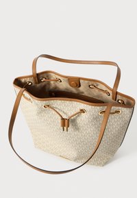 Beige tote bag met patroon en tan leren accenten, sluiting met trekkoord en gouden hardware; ruime binnenkant met ritsvak.