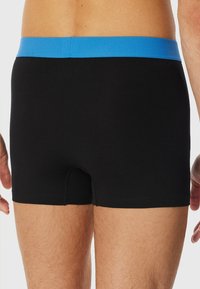 Black boxer shorts with a blue elastic waistband. The fabric appears smooth and stretchy, featuring a fitted design and minimal seams.