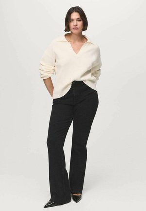 White ribbed sweater with a V-neck and rolled sleeves, paired with high-waisted black flared jeans and black pointed-toe heels.