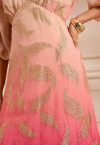 Vestido degradado en rosa con bordado de plumas metálicas en dorado, tejido ligero con una textura suave y una silueta elegante y fluida.