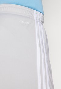 Šedé športové šortky s bielymi pruhmi, s elastickým pásom a logom "AEROREADY". Vyrobené z tkaniny odvádzajúcej vlhkosť.