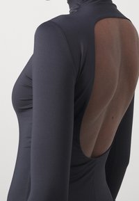 Body noir à manches longues avec un col montant, une coupe ajustée et un grand dos ouvert avec des panneaux transparents. Texture lisse, coutures minimales.