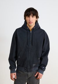 Mornarska zip-up kapuca, izdelana iz trpežne tkanine; ima kapuco z vrvico, kenguru žep in rebraste manšete z logotipom.