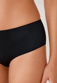 Black bikini bottom with a smooth, matte texture and a classic cut. No visible patterns or hardware, minimal branding on the side.