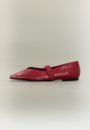 Zapato plano de cuero rojo con una correa fruncida en la parte superior y una puntera cuadrada, mostrado de lado sobre un fondo neutro.