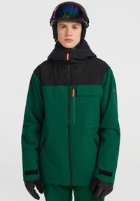 Grøn og sort isoleret skijakke med lynlåslommer, justerbar hætte og orange detaljer. Materialet ser glat og vandtæt ud.