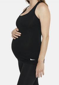 Czarny bezrękawnik ciążowy o dopasowanym kroju z białym logo Nike na dolnym brzegu. Gładka tekstura i lekki materiał.