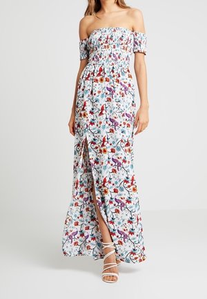 Robe maxi épaules dénudées bleu clair avec un motif floral en rouge, rose et vert ; comporte un corsage smocké et une fente latérale.