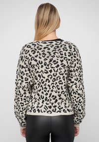 Knit genser med leopardmønster i svart og krem, med en avslappet passform, ribbestrikkede mansjetter og søm, myk tekstur og klassisk rund hals.