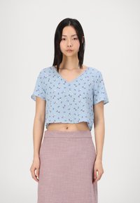 Top corto de manga corta con escote en V en azul claro con un patrón floral; hecho de una tela suave, presenta un ajuste relajado y un dobladillo recortado.