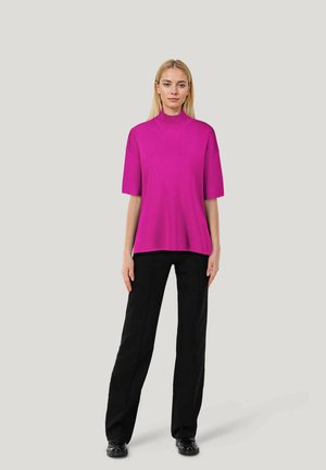 Fuchsia-farbenes Kurzarmoberteil mit hohem Kragen, lockerer Passform, glatter Textur, kombiniert mit schwarzen Hosen und schwarzen Schuhen. Einfaches Design, ohne Muster.