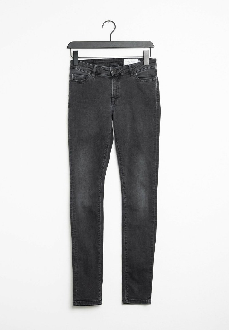 Musta skinny farkut roikkumassa mustassa ripustimessa valkoista taustaa vasten, jossa näkyvät etutaskut ja nappisulku.