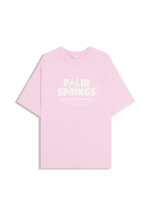 Lyserød kortærmet oversize T-shirt med teksten "Palm Springs" og "Sunset Resort Club" samt en søstjerne-grafik på fronten.