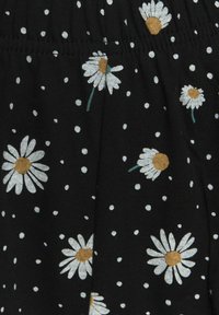 Schwarzer Stoff mit weißen Gänseblümchen mit gelben Mittelpunkten und grünen Stielen, vor einem Hintergrund aus kleinen weißen Punkten.