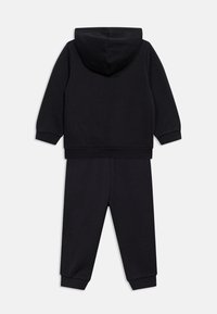 Μαύρο φούτερ με κουκούλα και ταιριαστό παντελόνι φόρμας τοποθετημένα επίπεδα, με θέα από πίσω, με ριμπ τελειώματα στα μανίκια και στη μέση.