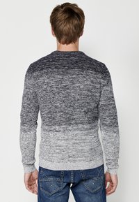 Grijze ombre gebreide trui met een ronde halslijn en lange mouwen, die overgaat van donker naar licht, met ribbels aan de manchetten en de zoom.
