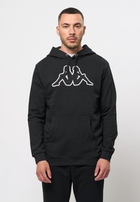 Zwarte hoodie met een voorzak, voorzien van een witte geborduurde logo van twee figuren. Zacht materiaal met een regular fit en verstelbare capuchon.