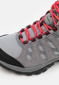Szare buty trekkingowe z siateczkowym wierzchem, czerwono-czarne sznurówki oraz trwała gumowa podeszwa z teksturowanym bieżnikiem. Wyróżniającym akcentem jest logo Columbia.