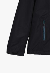 Mørkeblå jakkeærme med en lomme med lynlås, der har en lys blå lynlås. Materialet fremstår glat med en mat overflade, velcro-manchet.