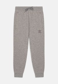 Sive hlače od trenirke s elastičnim pojasom, bočnim džepovima i rebrastim manžetama. Na lijevom bedrovu se nalazi tamno sivi Adidas logo.