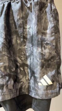 Βερμούδα με καμουφλάζ σε αποχρώσεις του γκρι με ελαστική μέση. Διαθέτει λευκό λογότυπο Adidas με τρεις ρίγες στο κάτω δεξί μέρος.