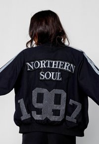 Must must jacket musta ja musta, mis on varustatud hõbedase "NORTHERN SOUL" tikandi ja "1987" plaastriga. Pehme materjal kontrastsete varrukaribadega.