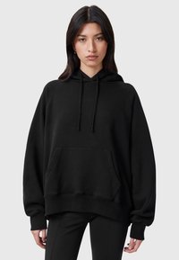 Svart oversized huvtröja i mjukt tyg, med en frampocket, snörning i huvan och ribbade muddar. Slät textur och avslappnad passform.